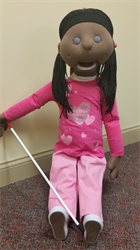 a photo of Gina the puppet, she resembles an African American girl and has a walking stick