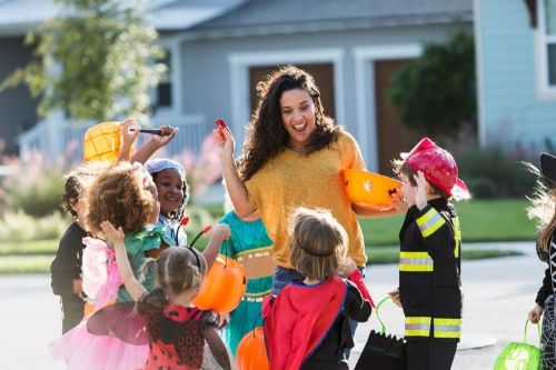 a photo of a woman passing out candy to tricker treaters