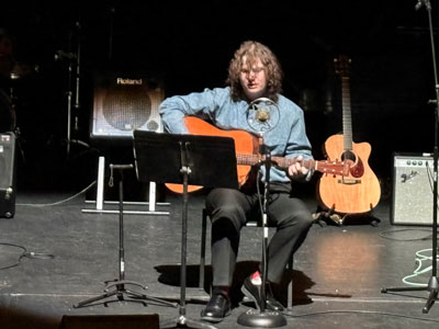 Samual on stage playing the guitar