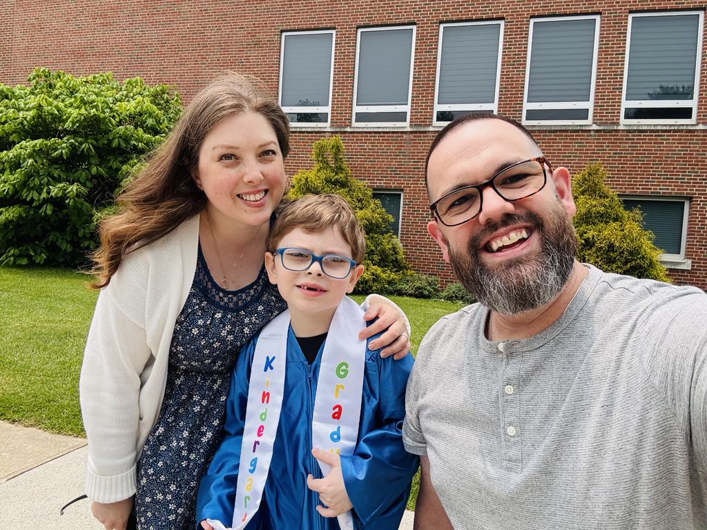 John Daniel standing with his parents at his kindergarten graduation