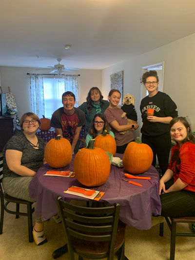 a fall photo of Rachel and her family at table surrounded by pumpkins